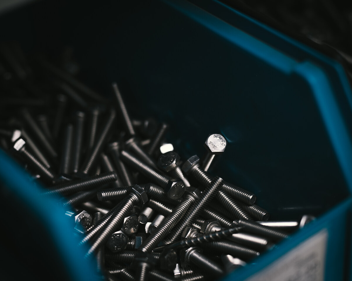 Close-up of loose screws in a teal bin